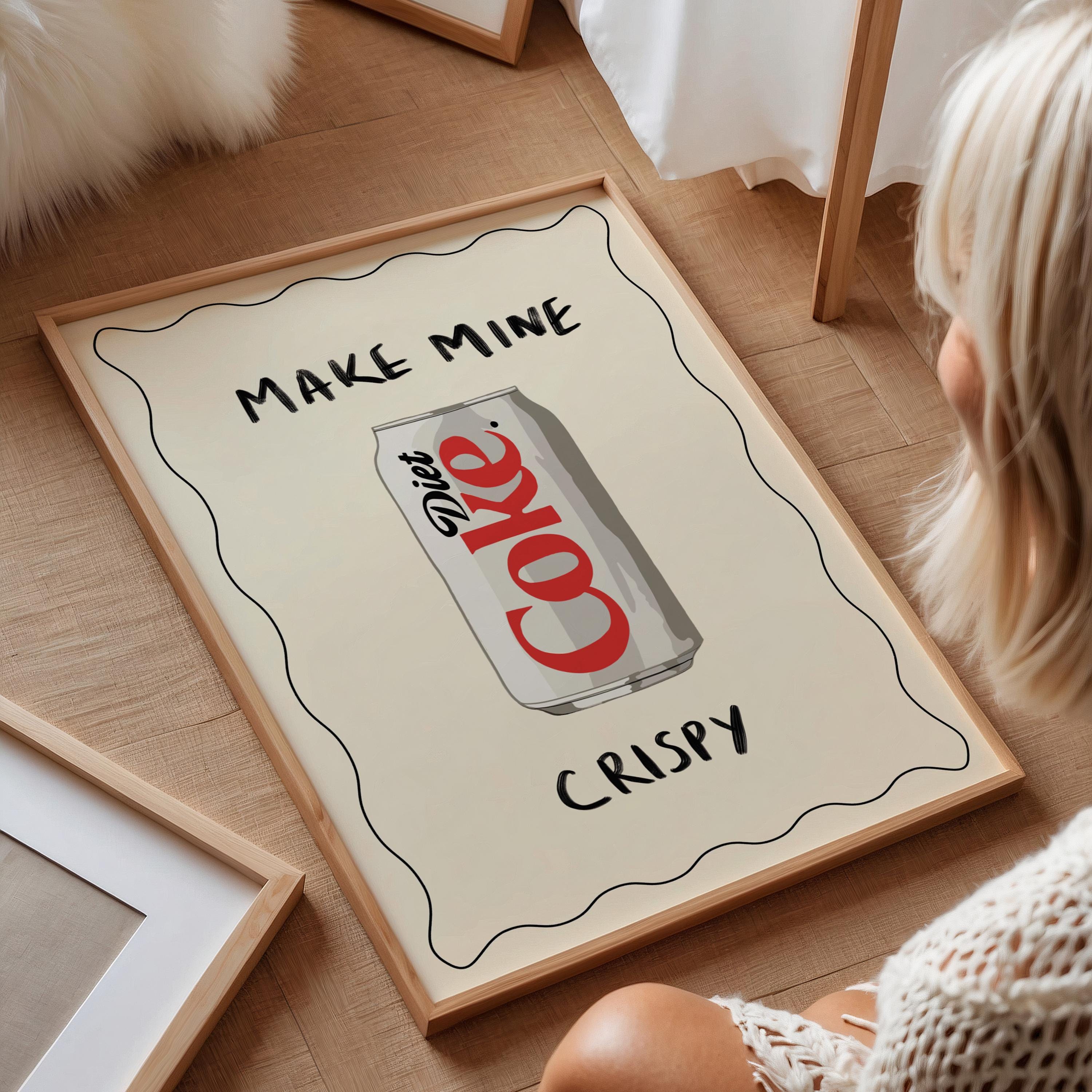 Framed poster with Diet Coke can design and text on a wooden floor.
