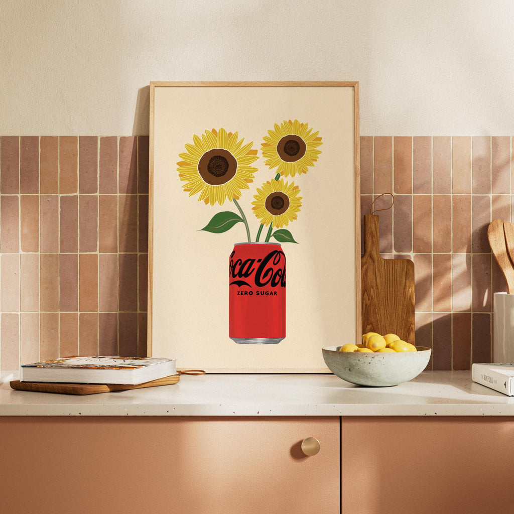 Framed artwork of a Coca-Cola can with sunflowers on a kitchen wall.