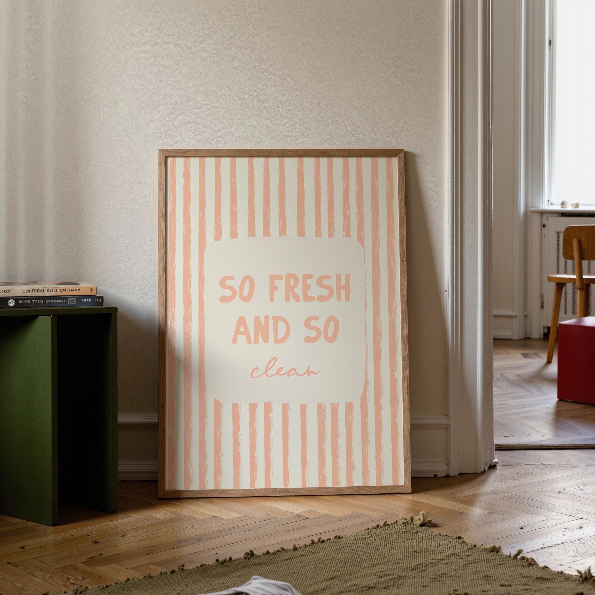 Framed poster with 'So fresh and so clean' text in a room with a green cabinet and wooden floor.