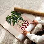 Person unrolling a large piece of paper with a plant design on a light-colored floor.