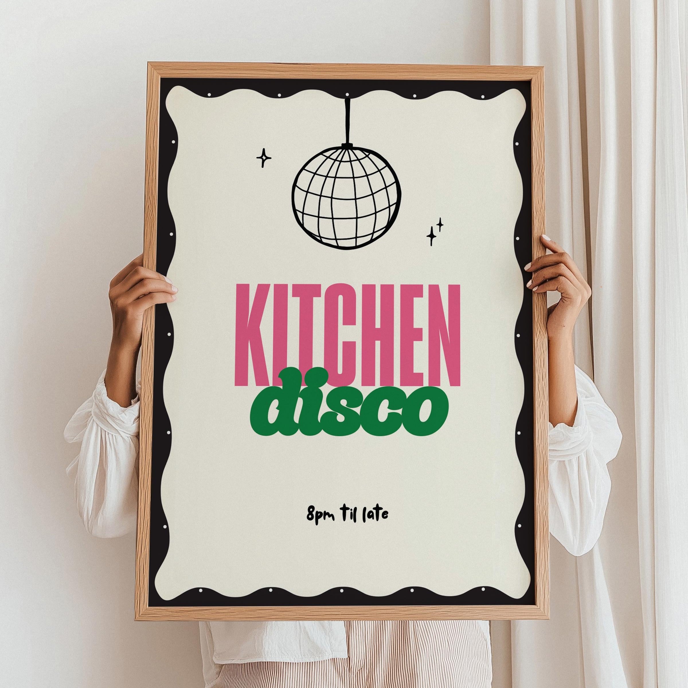 Person holding a framed poster with 'Kitchen Disco' text and disco ball design.