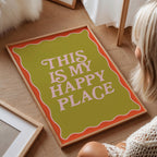 Person sitting on a wooden floor next to a decorative sign that reads 'This is my happy place'.