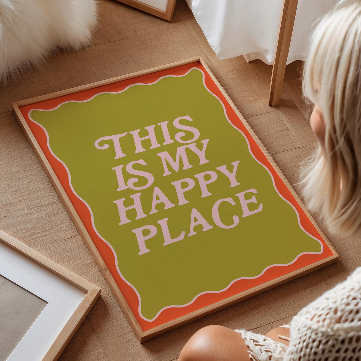 Person sitting on a wooden floor next to a decorative sign that reads 'This is my happy place'.