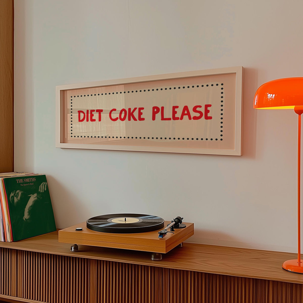 Wooden turntable with vinyl records on a wooden shelf, framed sign above reading 'Diet Coke Please', and orange lamp.