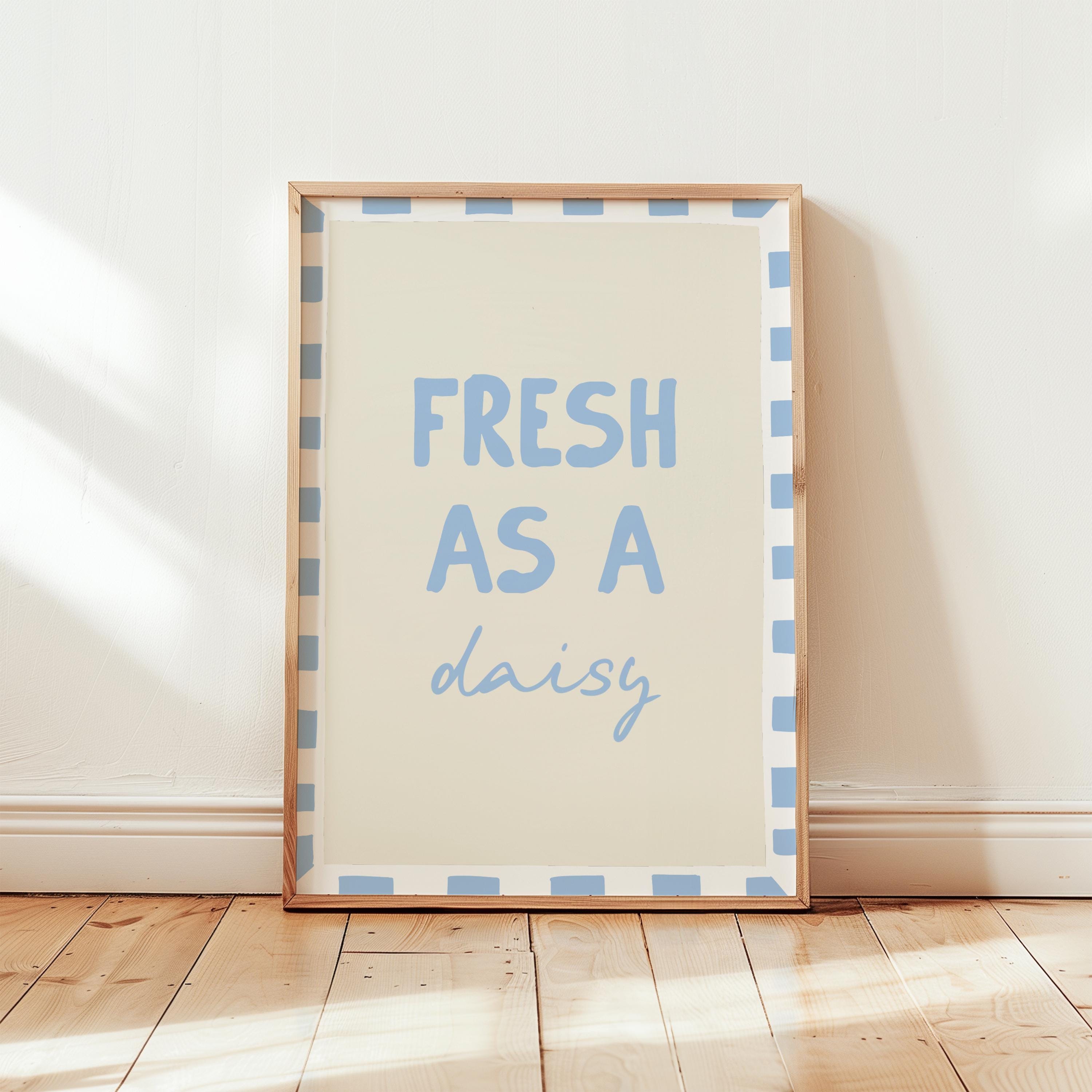 Framed print with 'Fresh as a daisy' text on a wooden floor.