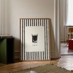 Framed artwork with a black and white design in a room with a green bookshelf and wooden floor.