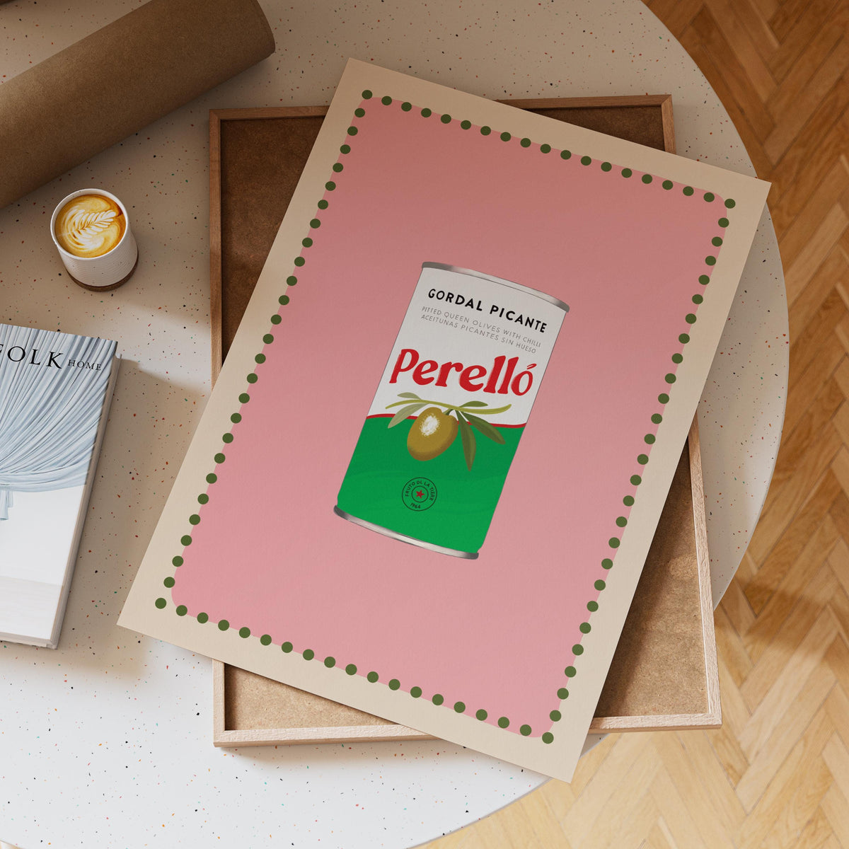 Framed artwork of a Perello can on a table with a cup of coffee and book.