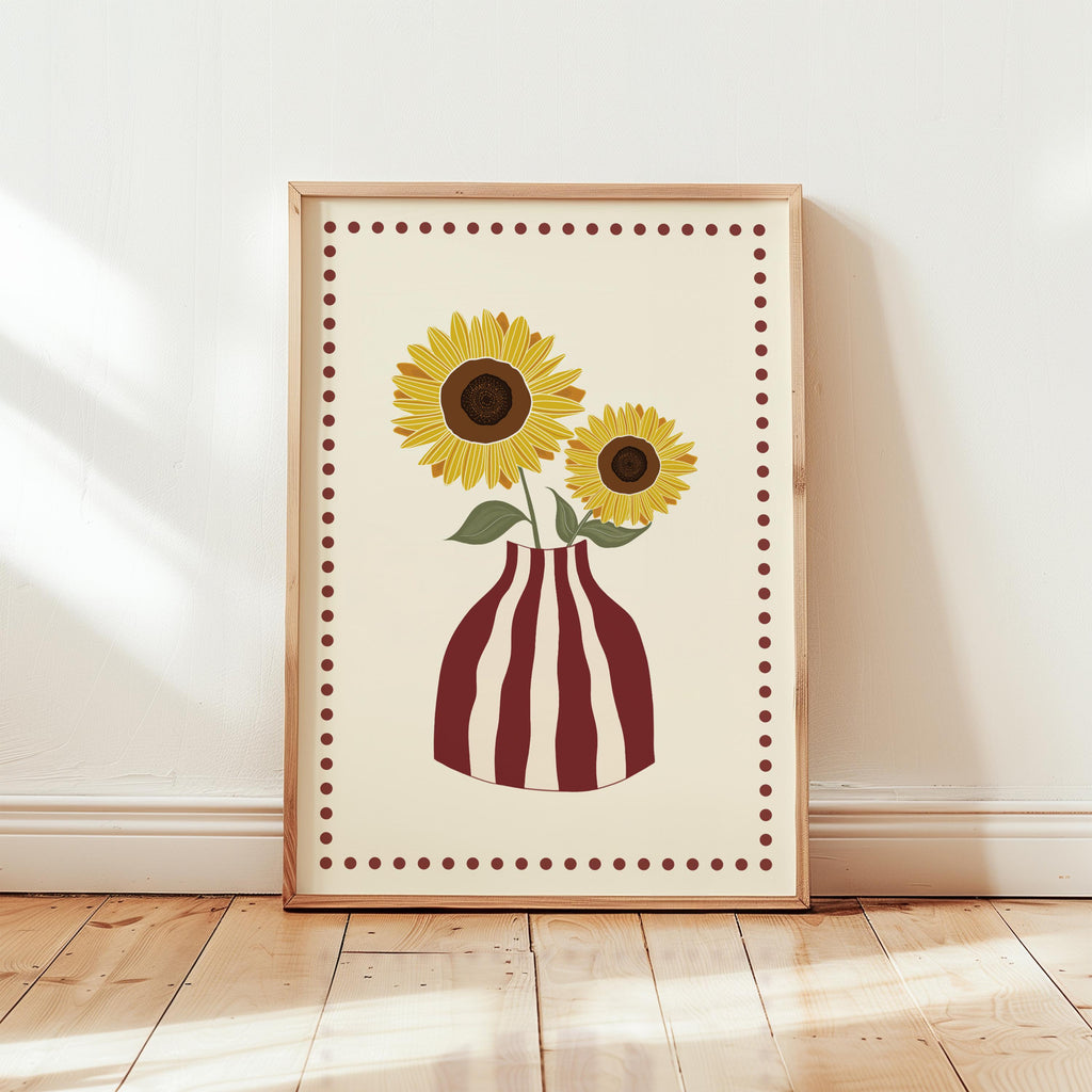 Framed artwork of sunflowers in a striped vase on a wooden floor.