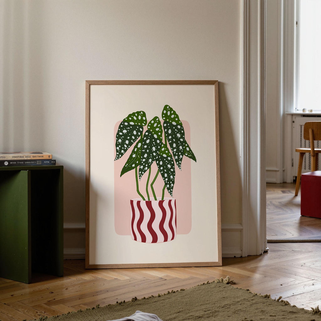 Framed artwork of potted plants on a wall in a room with a green bookshelf and wooden floor.