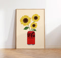 Framed artwork of sunflowers emerging from a Coca-Cola can on a beige background