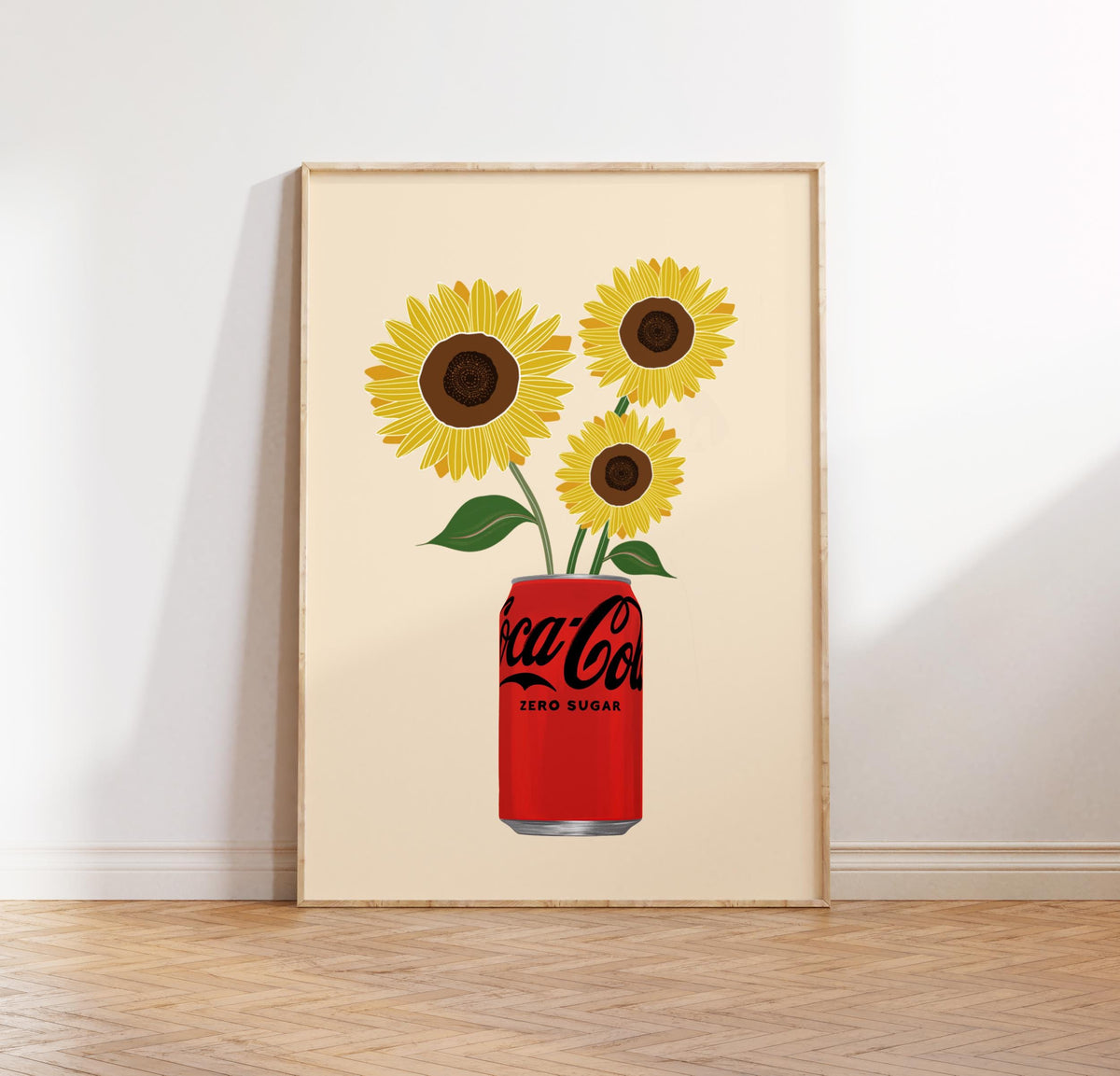 Framed artwork of sunflowers emerging from a Coca-Cola can on a beige background