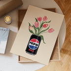 Pepsi Max can with tulips on a beige card, placed on a wooden surface with a cup of coffee.