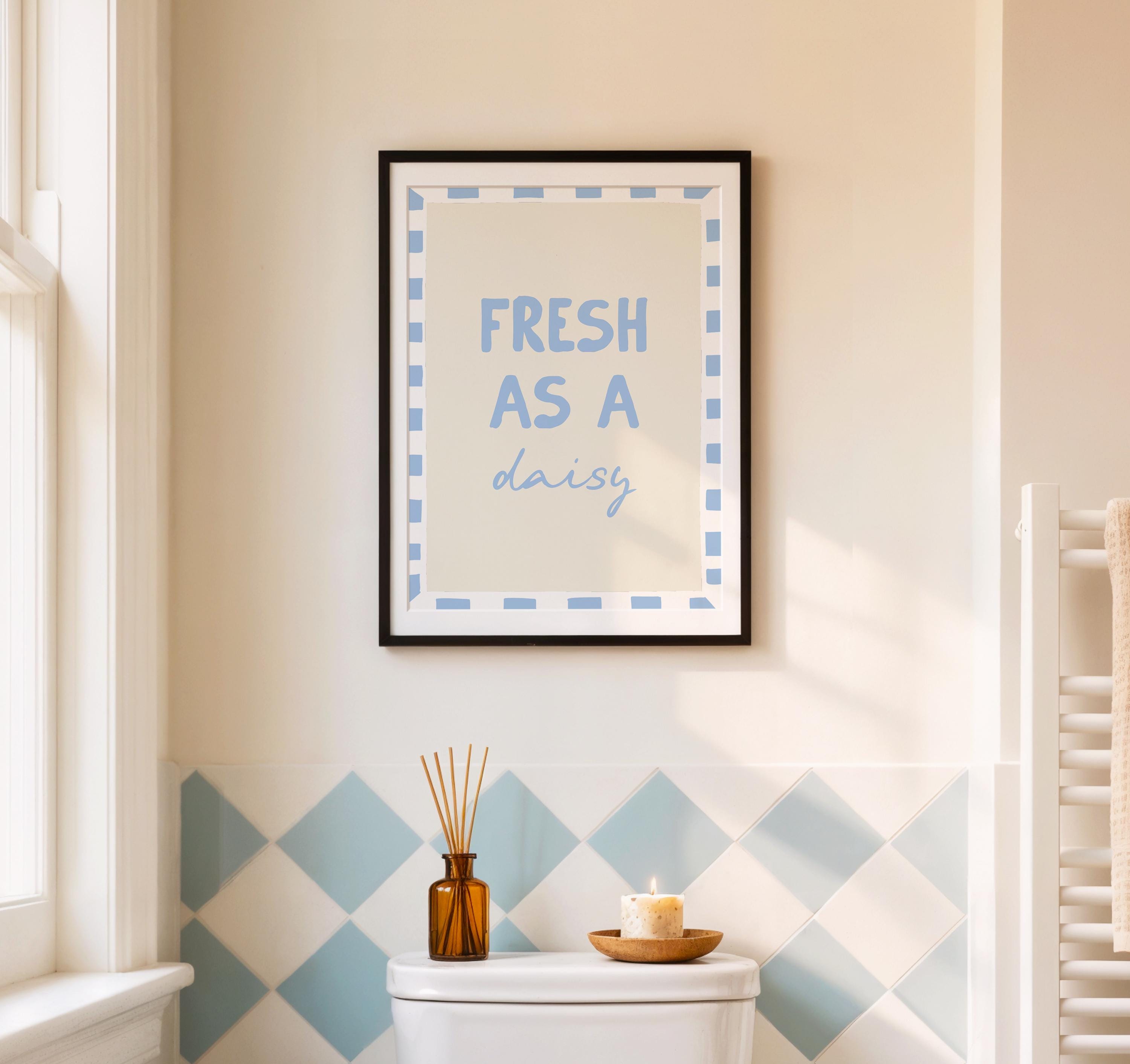 Framed artwork with 'Fresh as a daisy' text on a wall with geometric tile pattern.