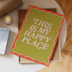 Decorative sign with 'This is my happy place' text on a table with a cup of coffee.