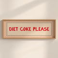Framed sign with 'Diet Coke Please' text on a beige wall