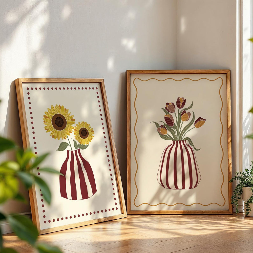 Two framed artworks of sunflowers and tulips on a wooden floor with plants around.