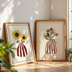 Two framed artworks of sunflowers and tulips on a wooden floor with plants around.