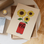 Notebook with Coca-Cola Zero Sugar design featuring sunflowers on a wooden surface.