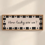 Decorative sign with 'How lucky are we?' text on a wall.