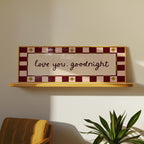 Decorative sign with 'love you, goodnight' text on a shelf against a wall.