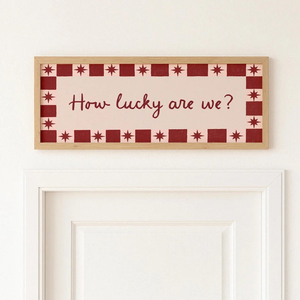 Decorative wall art with 'How lucky are we?' text on a white wall.