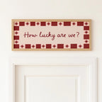Decorative wall art with 'How lucky are we?' text on a white wall.