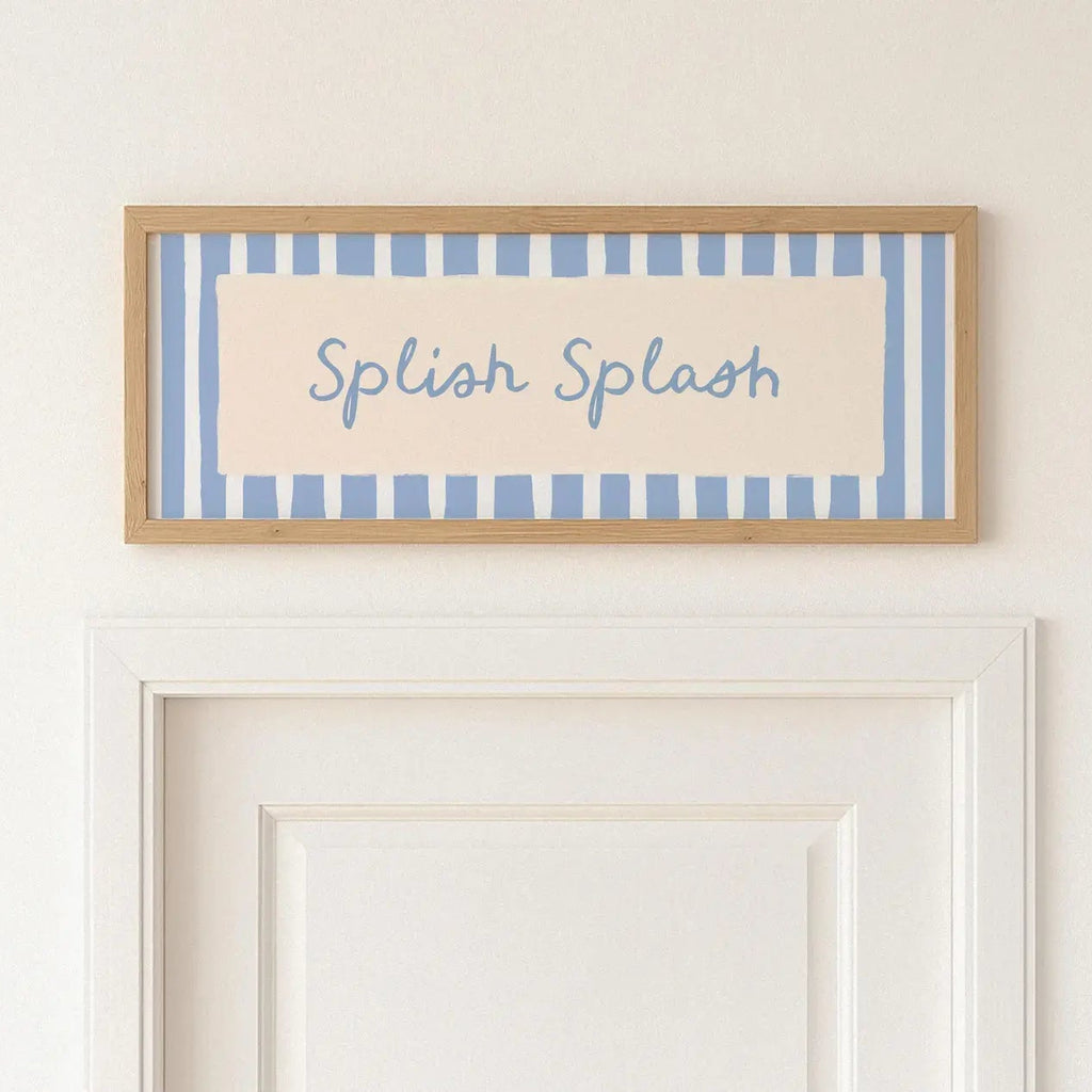 A framed decorative sign with the words 'Splash Splash' in blue script over a cream background and light blue vertical stripes, hung on a white wall above a white door.