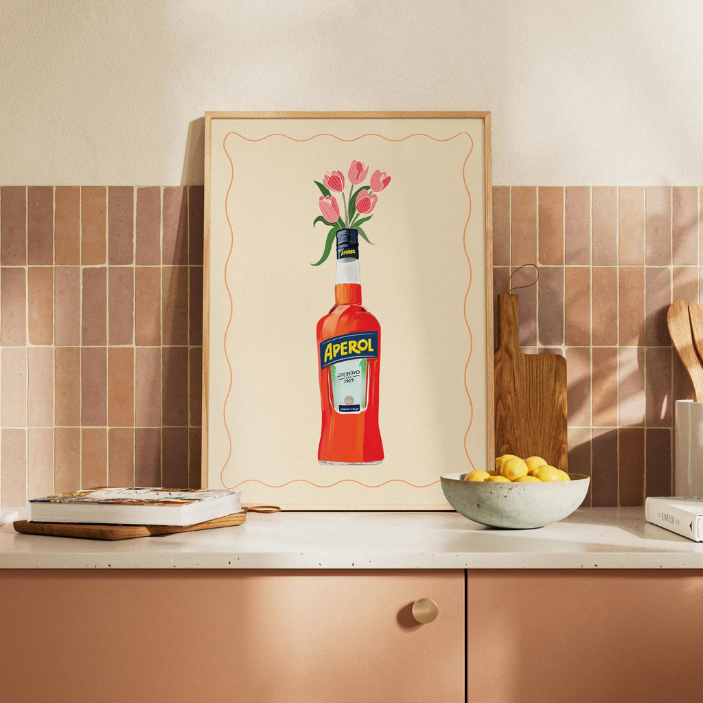 Kitchen with Aperol bottle artwork on the wall, wooden cutting board, and fruit bowl.