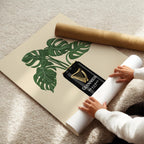 Person unrolling a large paper with a plant design and Guinness bottle graphic on a carpeted floor.
